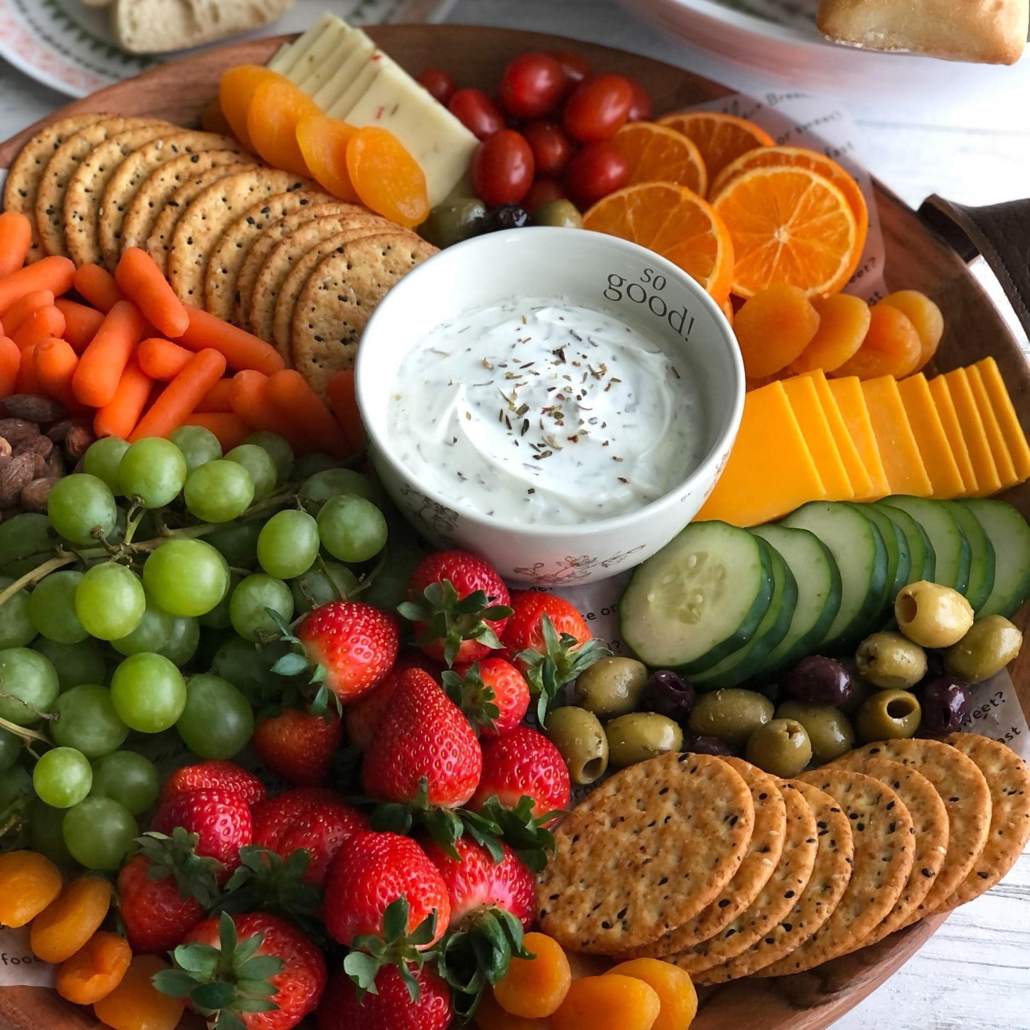 “A colorful assortment of fresh fruits, vegetables, crackers, and cheese on wooden serving boards.”